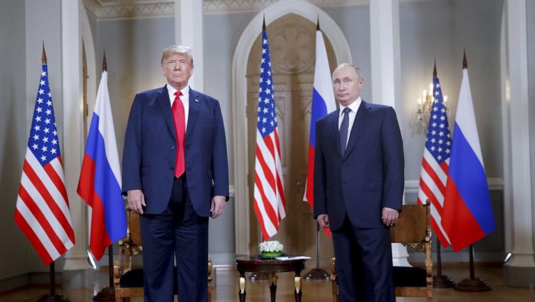 A person wearing a suit and tie standing in a room Description automatically generated