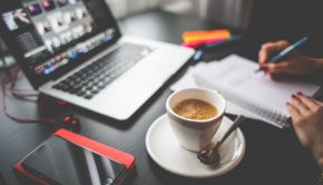 Coffee-filled Cup on Saucer Beside Macbook and Iphone on Desk