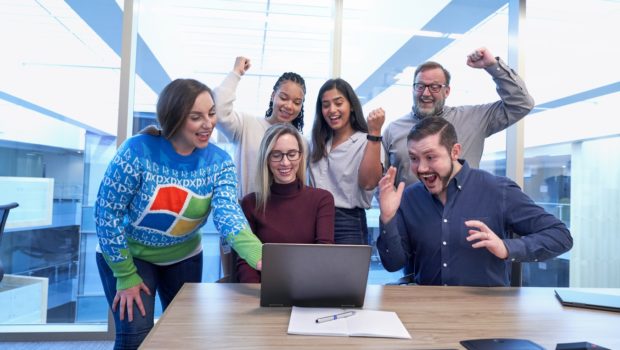 A group of people sitting at a table in front of a computer Description automatically generated