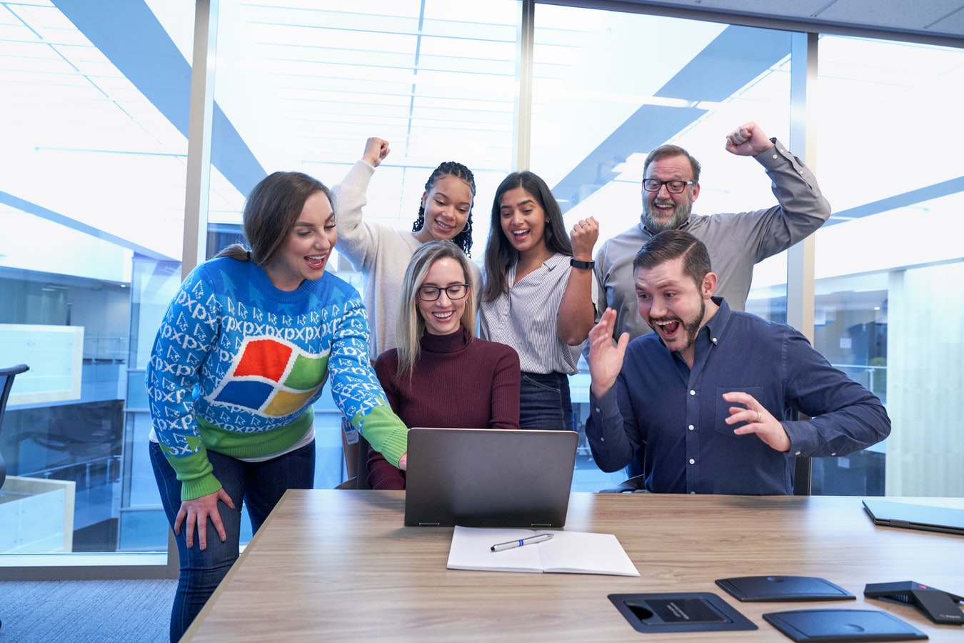 A group of people sitting at a table in front of a computer Description automatically generated