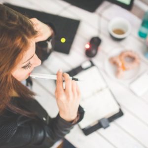 Young woman thinking with pen while working / studying at her desk