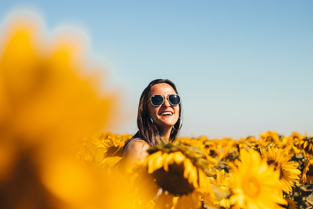 woman in black sunglasses on yellow flower field during daytime